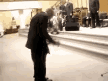 a man in a suit is standing on a stage in a church holding a bible .