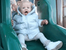 a baby is sitting on a slide with her tongue hanging out