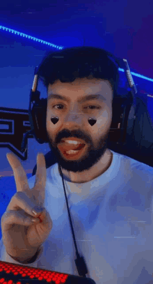 a man with a beard wearing headphones is making a peace sign .