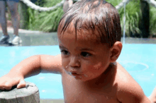 a baby without a shirt is standing in the water