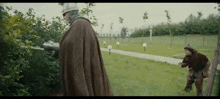 a man in a brown cape is standing next to another man in a helmet .