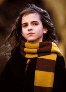 a young girl wearing a striped scarf looks at the camera