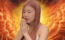 a woman with pink hair is praying with her eyes closed in front of a fire .