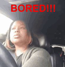 a woman sitting in a car with the word bored written on the top of her head