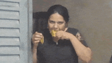 a woman in a black shirt is eating a banana .