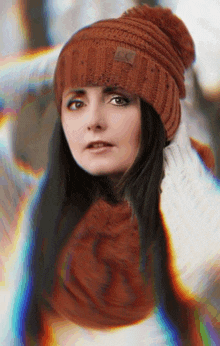 a woman wearing a knitted hat and scarf has a blurry background