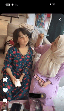 a woman in a hijab is applying makeup to a little girl 's face