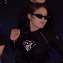 a woman wearing sunglasses and a black shirt with the word water on it is in a pool .