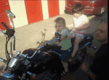 a boy and a girl sit on a motorcycle while a man watches