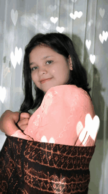 a girl in a pink shirt is standing in front of a window with hearts on it