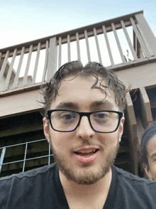 a man with glasses and a beard is smiling in front of a deck