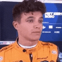 a close up of a young man wearing a yellow race car jacket .