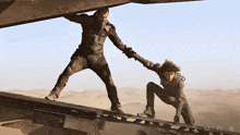 a movie poster for dune shows a man helping a woman up a ramp