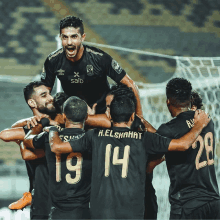 a group of soccer players wearing black shirts with the number 19 14 and 28 on them