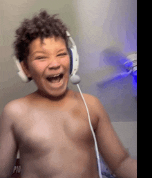 a shirtless boy wearing headphones and a microphone is smiling