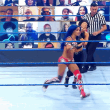 a woman in a wrestling ring with a referee in front of a screen that says ' the next time ' on it