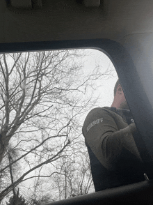 a man wearing a sheriff vest looks out the window