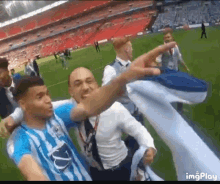 a group of men are standing on a soccer field and one of them is pointing at the camera .