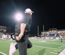 a man kneeling on a football field with a scoreboard in the background that says ' texas ' on it