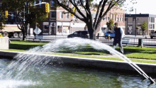 a fountain is spraying water in a park in front of a building that says ' abercrombie & fitch ' on the side