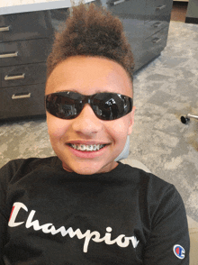 a boy wearing sunglasses and a black champion shirt