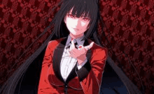 a girl with long black hair is wearing a red suit and tie and pointing at the camera .