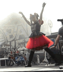 a woman in a red dress is dancing on a stage in front of a sign that says ' pan '