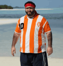 a man with a beard and a headband is wearing an orange and white striped shirt with the number 10 on it .