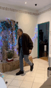 a man is dancing in a room with christmas lights