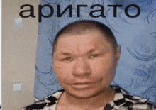 a man with a shaved head is standing in front of a blue curtain with the word apigato written on it