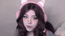 a young woman wearing a pair of pink cat ears headphones .