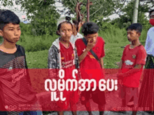 a group of young boys are standing in a field and one of them is wearing a red shirt that says ' liverpool '