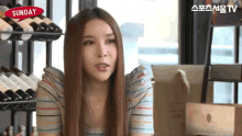 a woman sitting in front of a shelf of wine bottles with a speech bubble that says " sunday "