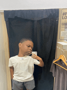 a young boy taking a picture of himself in a dressing room with a sign that says lg