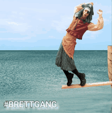 a man in a pirate costume is balancing on a wooden plank over the ocean