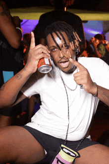 a man with dreadlocks is holding a can of soda