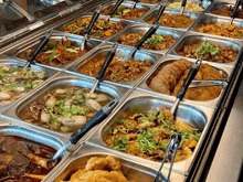 a buffet filled with lots of different types of food and tongs .