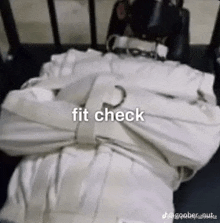 a person in a straitjacket is laying on a bed with the words `` fit check '' written on it .