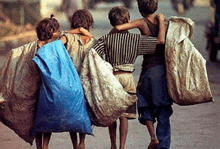 a group of children are walking down a street with bags on their shoulders .