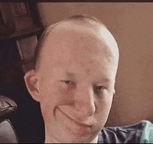 a man with a bald head is making a funny face while sitting on a couch .