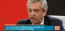 a man in a suit and tie is on a television screen with the words " alberto fernandez " at the top