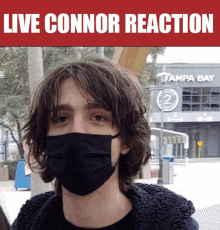 a man wearing a face mask is standing in front of a building that says tampa bay