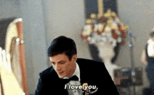 a man in a tuxedo is saying i love you in a room .