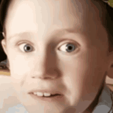 a close up of a child 's face with a surprised look on his face