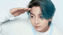 a man with blue hair salutes with his hand on his forehead