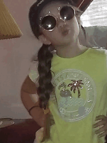 a little girl wearing sunglasses and a yellow shirt that says sunny day