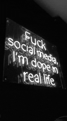 a neon sign that says " fuck social media i 'm dope 'n real life "