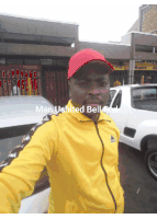 a man wearing a yellow jacket and a red hat is standing in front of a building that says man united bell