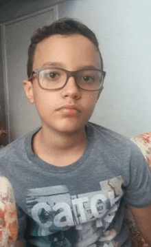 a boy wearing glasses and a shirt that says " catch "