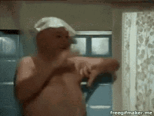 a shirtless man with a towel on his head is in a bathroom .